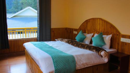 a bedroom with a large bed with a large window at The Woodpecker Inn Jibhi in Jibhi