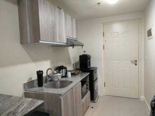 a small kitchen with a sink and a refrigerator at feliz studio condo at banilad in Cebu City