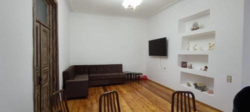 ein Wohnzimmer mit einem schwarzen Sofa und einem TV in der Unterkunft Ganja house in Ganja