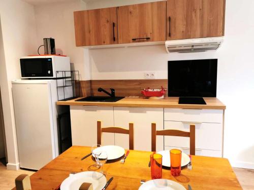 - une cuisine avec une table en bois, des chaises et un comptoir dans l'établissement Résidence Bourgeon - Le Bourgeon 7 - Joli studio divisible, classé 2 étoiles MAE-4514, à Valmorel