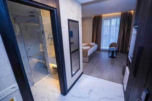 ein Bad mit einer Dusche und einem Spiegel im Zimmer in der Unterkunft Arium Hotel Baku in Baku