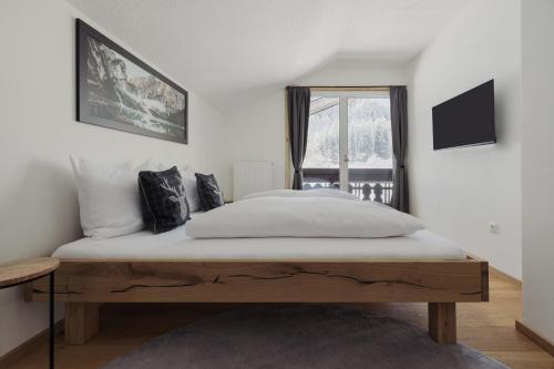 a bedroom with a bed with white sheets and a window at Ferienhaus Streif LXL in Kirchdorf in Tirol