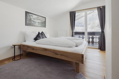 a bedroom with a bed with white sheets and a window at Ferienhaus Streif LXL in Kirchdorf in Tirol