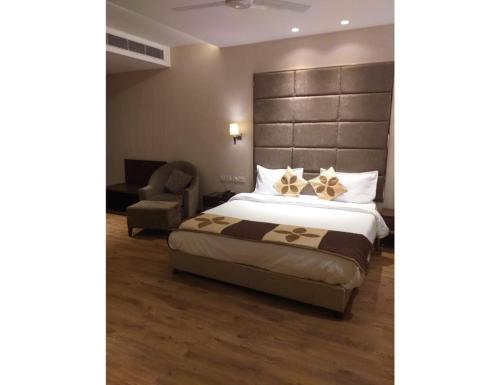 1 dormitorio con 1 cama grande y 1 silla en Hotel Golden Palm, Gurdaspur, en Gurdāspur