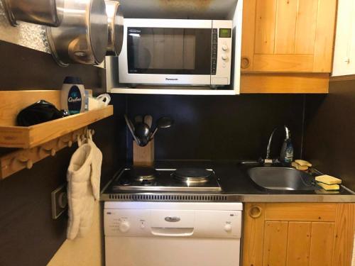 une petite cuisine avec une cuisinière et un micro-ondes dans l'établissement Résidence Roche Combe - Le Roche Combe 44 - Charmant studio divisible offrant une jolie vue. MAE-2841, à Valmorel