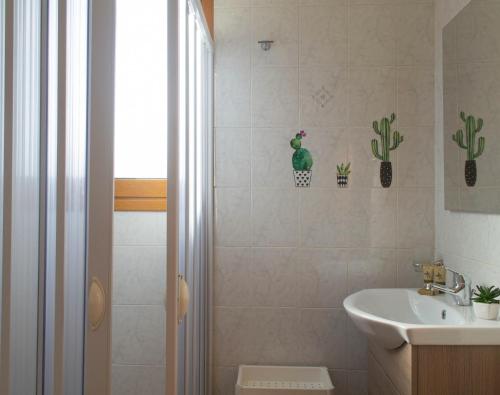 a bathroom with a sink and a shower with cactus stickers at Residence Tre Palme - Localo in Torre dell'Orso