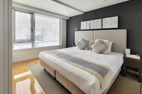 a bedroom with a large bed and a large window at Alpen Ridge in Niseko