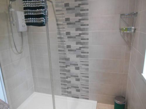 a shower with a glass door in a bathroom at Eliburn Woodside Lodge in Livingston