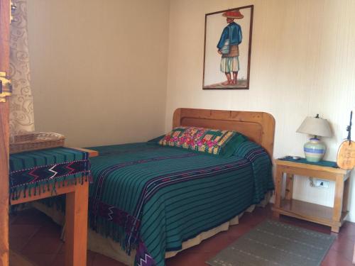 a small bedroom with a bed and a table at Posada De Los Volcanes in Panajachel