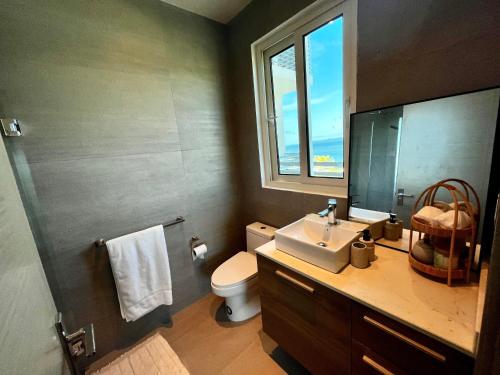 La salle de bains est pourvue d'un lavabo, de toilettes et d'une fenêtre. dans l'établissement Playa Escondida: Confort y relax en el Caribe, à María Grande