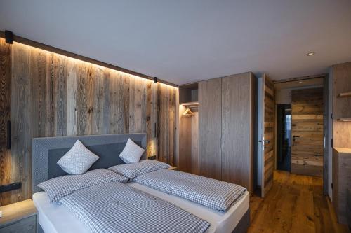 ein Schlafzimmer mit einem Bett mit einer Holzwand in der Unterkunft Rueper Hof Chalet Ruipa in Olang