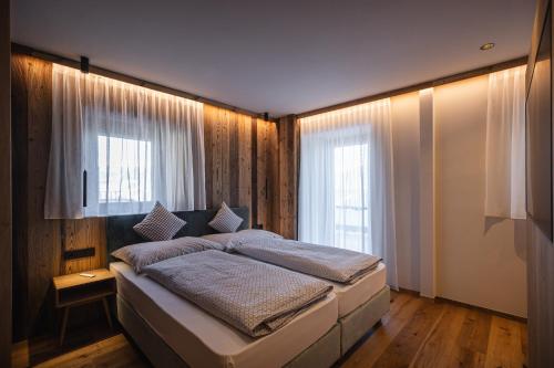 a bedroom with a large bed and two windows at Rueper Hof Chalet Pracken in Valdaora