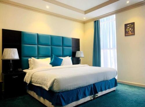1 dormitorio con 1 cama grande y cabecero azul en فندق ميلانا Milana Hotel en Yeda