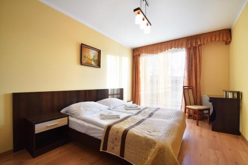 a bedroom with a bed and a desk and a window at Apartament 29 Zielone Tarasy Kołobrzeg in Kołobrzeg