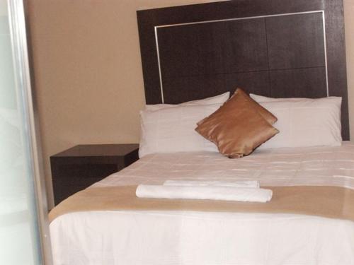 Cama con almohada marrón y almohadas blancas en DZUVHA VILLAGE INN, en Thohoyandou