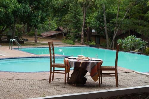 a table and two chairs in front of a pool at Star Dambulla in Dambulla