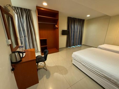 a hotel room with a bed and a desk and a bed and a chair at Aeton Hotel Nilai in Nilai