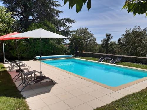 una piscina con sombrilla y 2 sillas en Domaine Les Feuillants, en Crouzilles