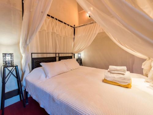 a bedroom with a white bed with curtains at Villa in Santorini with Stunning Outdoor Kitchen in Megalokhori