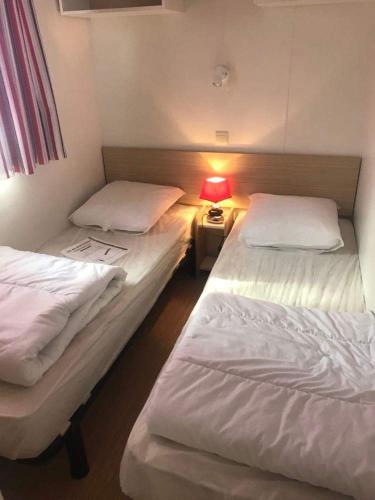 deux lits dans une chambre avec une lampe sur une table dans l'établissement Le bois dormant, à Saint-Jean-de-Monts