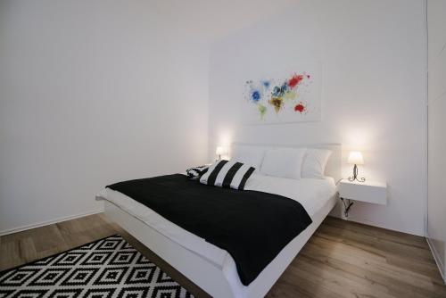 a white bedroom with a black and white bed and a table at Apartment British Square with parking in Zagreb
