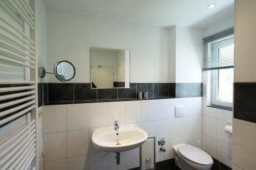 W łazience znajduje się umywalka, toaleta i lustro. w obiekcie Dat blaue Huus - Am Tor zum Darß w mieście Pruchten