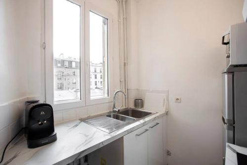 eine weiße Küche mit einem Waschbecken und einem Fenster in der Unterkunft COSY, DESIGN AND LUXURY APARTMENT, 5 MINUTS PARIS in Saint-Mandé