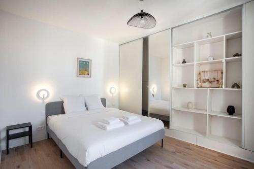 ein weißes Schlafzimmer mit einem großen weißen Bett und Regalen in der Unterkunft COSY, DESIGN AND LUXURY APARTMENT, 5 MINUTS PARIS in Saint-Mandé