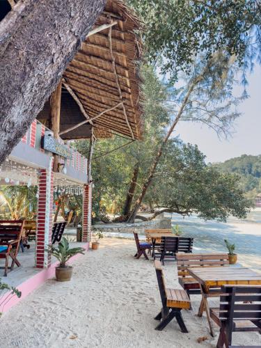 un grupo de bancos y mesas en la playa en Full Moon Bungalow Resort Koh Chang Ranong, en Koh Chang