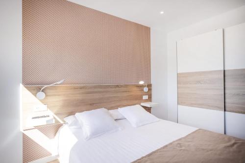 a bedroom with a white bed and a wooden headboard at Casa Senderos del Norte in Sauzal