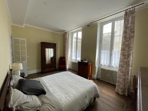 a bedroom with a bed and two windows at Jardin des Remparts in Orthez