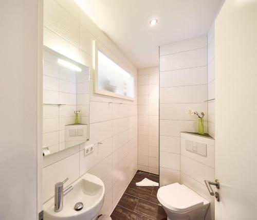 een witte badkamer met een wastafel en een toilet bij Nordico, FeWo 8 in Duhnen