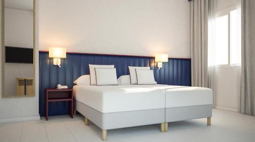 um quarto com uma cama branca e uma parede azul em Serena Majestic Hotel em Montesilvano