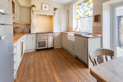 a kitchen with white cabinets and a wooden floor at Pebble Cottage in Seahouses
