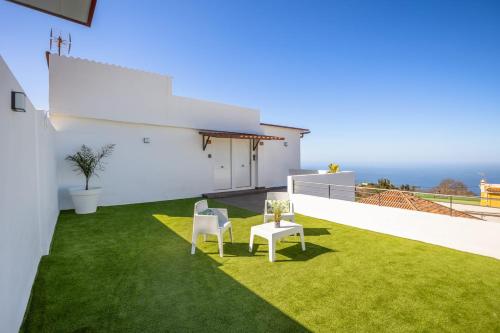 a white house with a green yard with two chairs at Casa Senderos del Norte in Sauzal