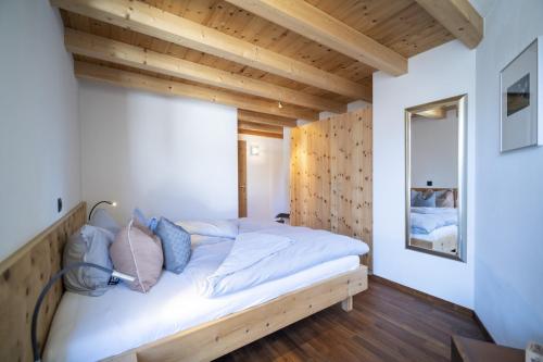um quarto com uma cama num quarto com tectos em madeira em Chasa Costa dad Archas Maisonette Wohnung em Scuol