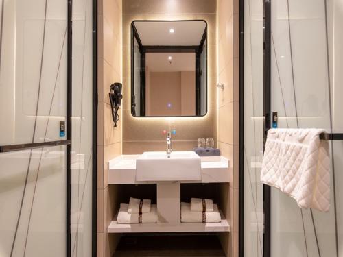 a bathroom with a sink and a mirror at Thank Inn Chain Jiaozuo Qinyang Qinbei Industral Cluster in Qinyang