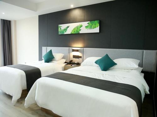 two beds in a hotel room with a tv on the wall at Thank Inn Chain Fuyang Linquan Stadium in Linquan