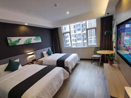 um quarto de hotel com duas camas e uma televisão de ecrã plano em Thank Inn Chain Hami Queen Sky Street em Hami