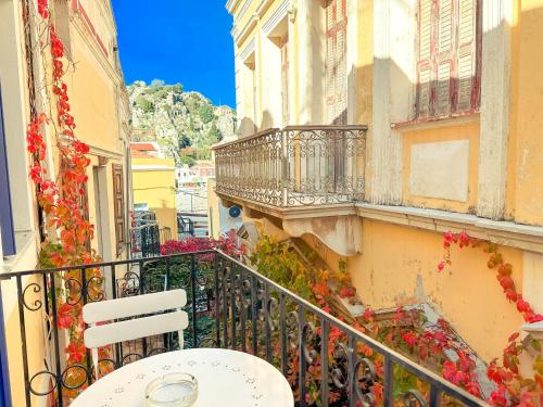 a balcony of a building with a white table and chairs at Kali Strata 2 - Downtown in Symi