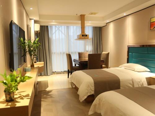 een hotelkamer met 2 bedden, een bureau en een tafel bij LanOu Hotel Impressions of Taipei Xiantao City in Xiantao