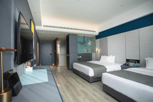 LianshuiにあるLanOu Hotel Huai'an Lianshui High-Speed Railway Station Yanhuang Avenueのベッド2台とテレビが備わるホテルルームです。