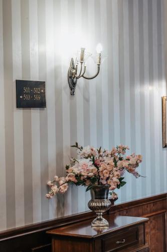 a vase of flowers on a table with a clock at Tbilisi Laerton Hotel in Tbilisi City