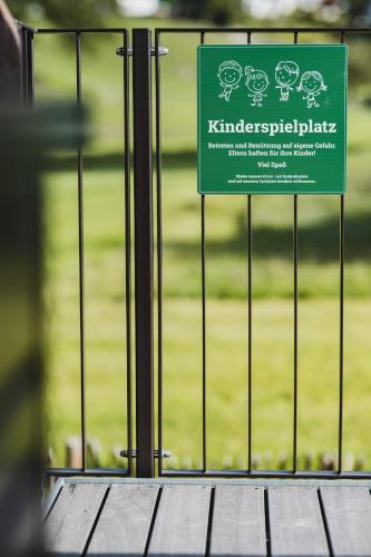 a green sign on a fence with a wooden table at TILL Naturhotel - Self-Check-In in Satteins