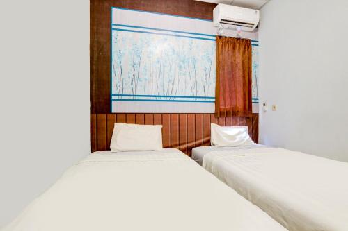 two beds sitting next to each other in a room at OYO Life 90388 De'leota in Semarang