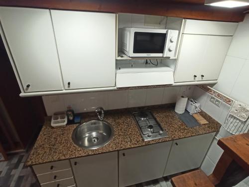 una pequeña cocina con fregadero y microondas en La Casita, en Gijón