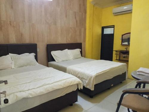 a bedroom with two beds and a chair in it at OYO 91232 Hotel Garuda in Sumenep