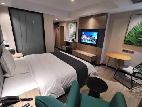 een hotelkamer met een bed en een televisie bij Thank Inn Chain Heyuan Zijin Baocheng Commercial Plaza in Zijin