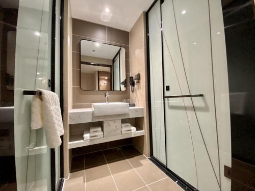 a bathroom with a sink and a mirror and a shower at Thank Inn Chain Suqian Hubin New District Santaishan Park in Suqian