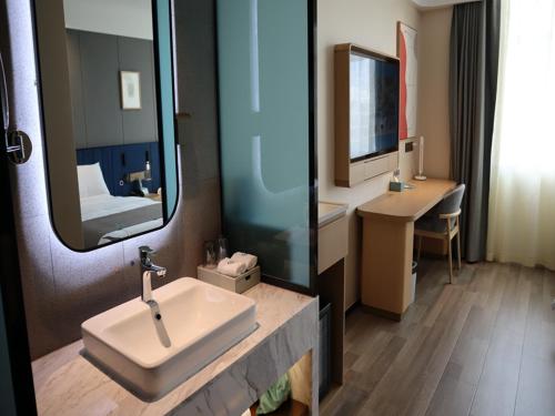 La salle de bains est pourvue d'un lavabo et d'un miroir. dans l'établissement LanOu Hotel Ordos Jungar Banner Jungar Street, à Jungar